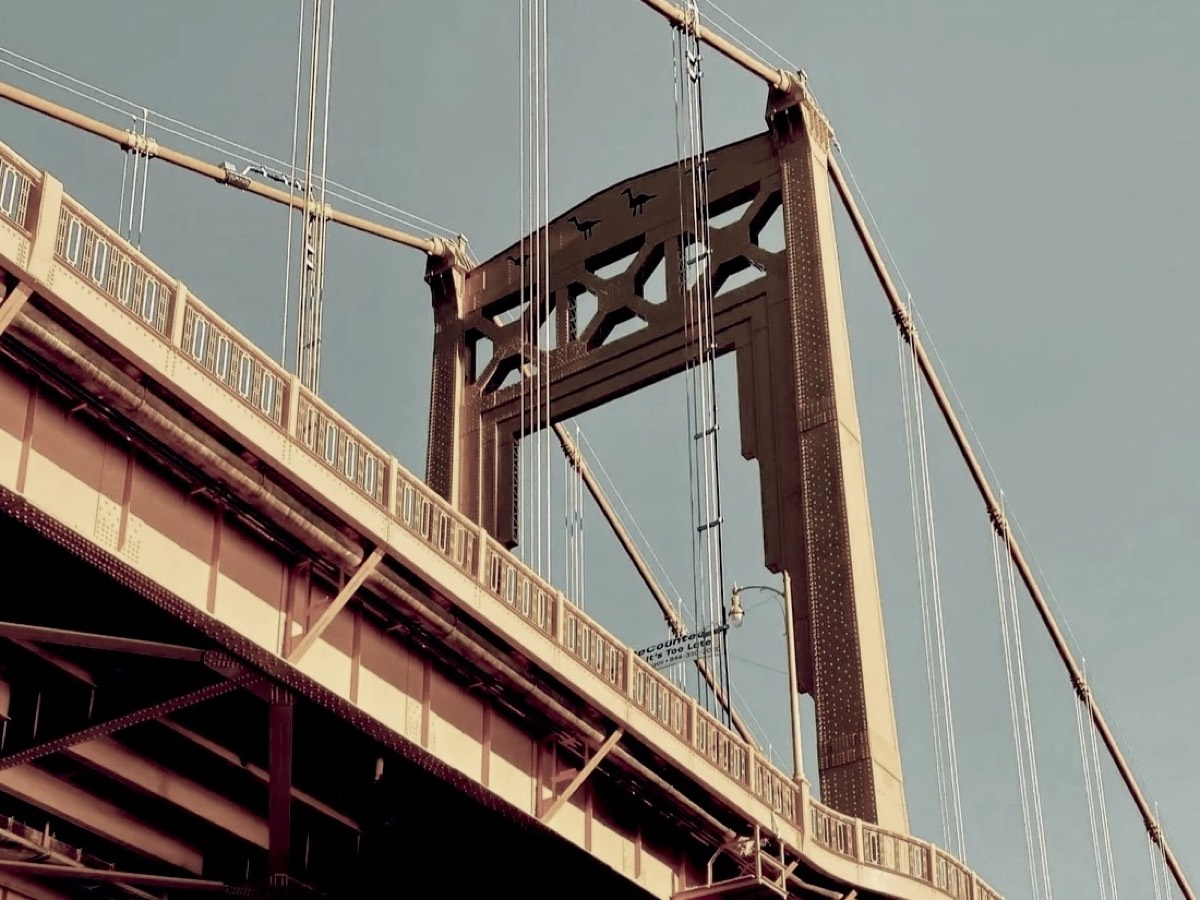 Close-up of a gold steel suspension bridge tower against the sky
